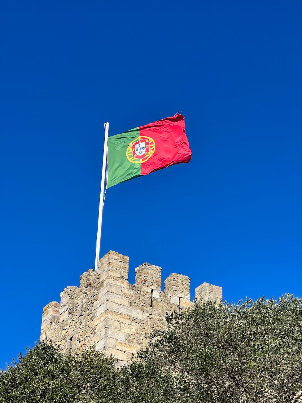 red and green portuguese flag on top of brown concrete building in Portugal